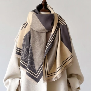 Plaid scarf with geometric patterns and tassels over a white wool coat on a mannequin