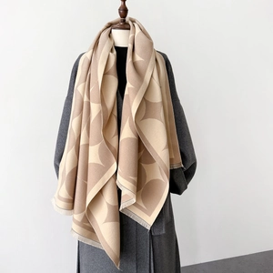 Detail of soft beige geometric knit shawl with short fringe on a wool coat