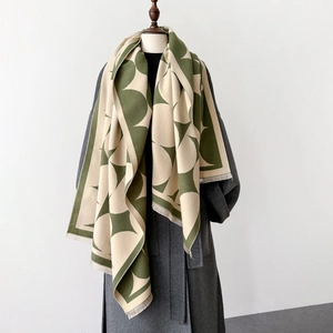 Detail of green and beige geometric knit shawl with fringes on a grey wool coat