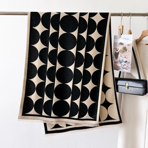 Detail of knitted beige scarf with large black polka dots and fine tassel edges