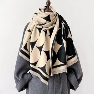 Close-up of geometric pattern scarf with fringe on a grey wool coat mannequin