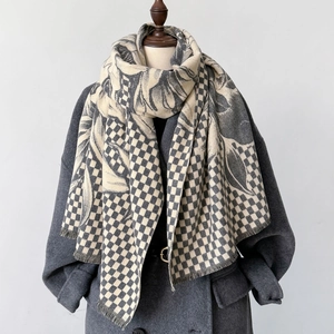 Plaid cashmere-like scarf with leaf pattern and tassels displayed on a grey coat