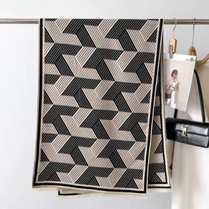 Detail of soft knit scarf featuring geometric black and white stripes and tassel trim edge