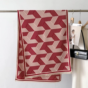 Close-up of red and white geometric arrow pattern knit scarf with fringe detail