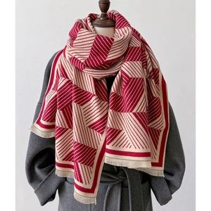 Detail of red and white geometric pashmina with fringe tassels on dark coat