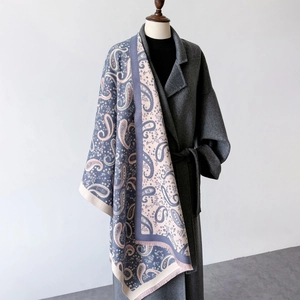 Detail of navy paisley jacquard shawl with tassel fringe draped over a grey coat