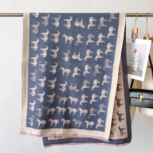 Detail eines Schals mit Pferde-Print und Quastenrand neben Luxus-Accessoires