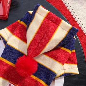 Detail of red and navy striped knit pet clothing with a soft red faux fur pom-pom ball