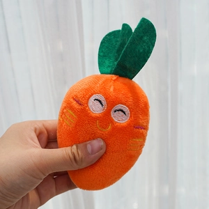 Close-up of hand holding plush carrot dog toy with cute embroidered facial expressions