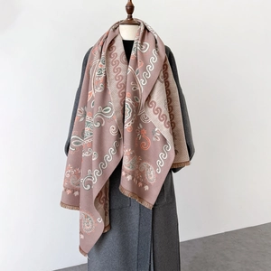 Détails des motifs paisley et des franges douces sur un châle rose et beige
