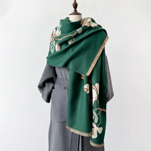 Detail of dark green knit shawl with white and pink magnolia floral prints and soft fringes