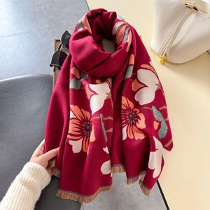 Detail of red floral scarf with soft tassels draped elegantly on a textured chair