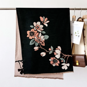 Close-up of double-sided shawl with magnolia print and fringe edge on a hanger