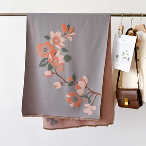 Detail of floral printed shawl with soft tassels showing grey and red reversible sides