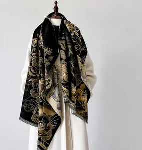Close-up of elegant floral print shawl with fine tassel edges on a white coat model