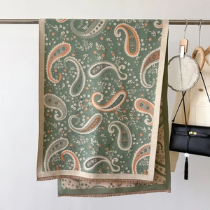 Close-up of vintage dark green paisley scarf with orange floral patterns and fringe
