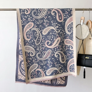 Detail of paisley pattern winter scarf with pink fringe and blue jacquard texture