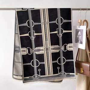 Détail d'une écharpe en cachemire avec motif équestre et franges sur un cintre