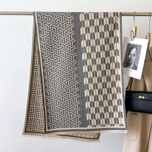 Detail of a luxury gray plaid knit scarf with geometric patterns and fringe edges