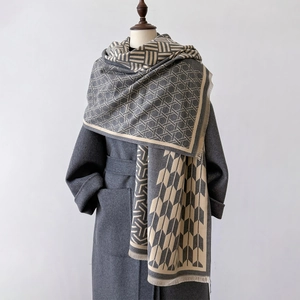 Detail of grey and beige geometric pattern scarf with fine fringe on a wool coat