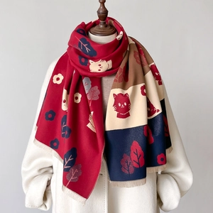 Detail of cashmere-like scarf showing cute cat patterns and knit tassels on mannequin