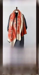 Detail of warm cashmere-feel winter scarf featuring orange floral patterns and soft fringes