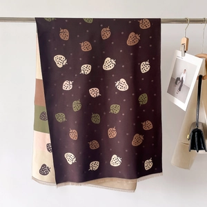 Detail of strawberry pattern scarf with fine tassel edges and warm earthy tones