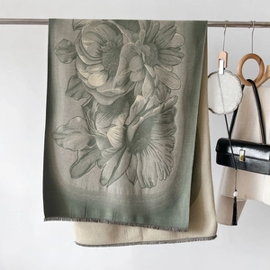 Detail of floral cashmere-feel scarf with elegant gray-green daisy pattern and soft fringes