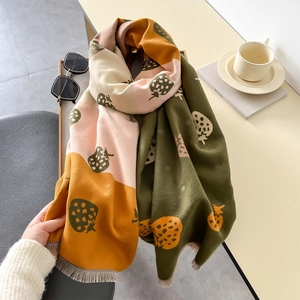 Detail of color-block scarf with strawberry prints and soft fringe edges on a table