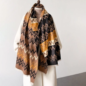 Detail of cashmere-like shawl with earth-tone zigzag patterns and delicate fringe
