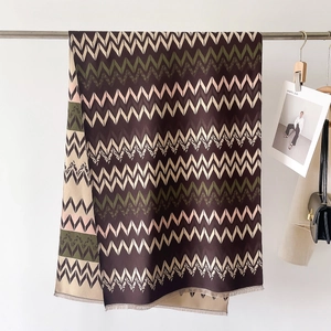 Detailed view of striped cashmere-like scarf with fringe edges and geometric patterns