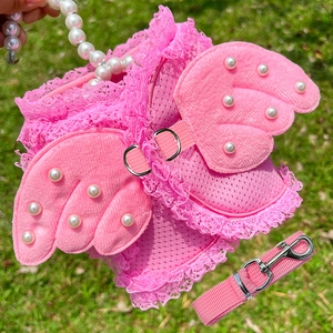 Detail of pink mesh dog harness with lace edges and pearl angel wing decorations