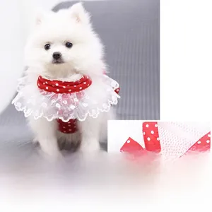 Dettaglio dell'imbracatura rossa a pois per cani con pizzo bianco e fiocco sul cane