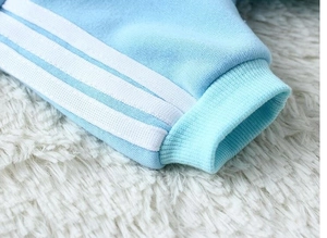 Close-up of ribbed cuff on light blue dog hoodie with three white sporty stripes