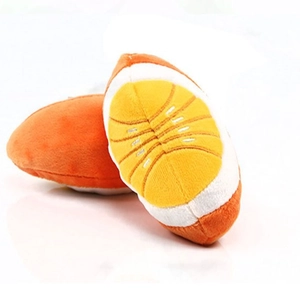 Plush orange rugby-shaped dog squeaky toy with citrus fruit design on white surface
