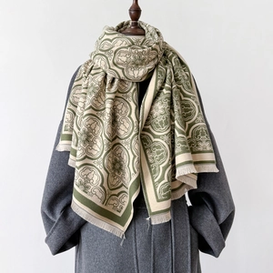 Écharpe épaisse à fleurs vert olive avec franges sur un manteau gris et fond blanc
