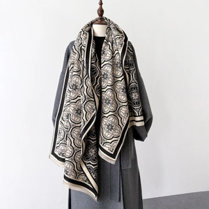 Détail d'un châle beige et noir élégant avec motifs floraux et finitions à franges