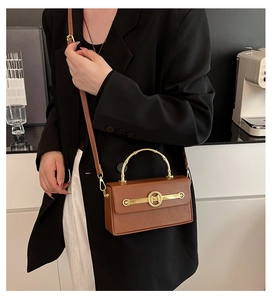 Detailansicht der braunen Kunstledertasche mit goldenem M-Logo und Bambusgriff