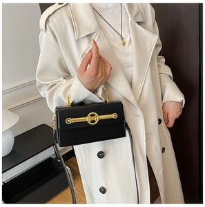 Detailansicht der schwarzen Lackledertasche mit goldener M-Schnalle und Ringgriff