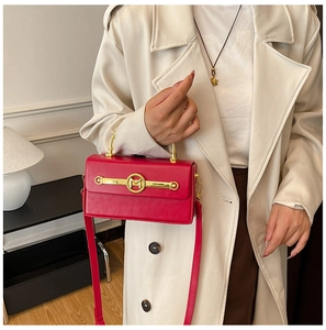 Detailansicht der roten eckigen Handtasche mit goldenem M-Logo und weißem Mantel