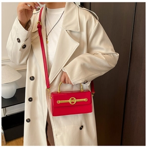 Detail der roten Lederhandtasche mit goldenem Metallgriff und M-Logo auf weißem Mantel