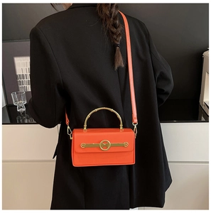 Detail der orangefarbenen Leder-Box-Tasche mit goldenem Bambusgriff und M-Ring-Verschluss
