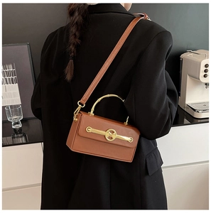 Braune Box-Tasche mit goldener M-Schnalle, am Modell in minimalistischer Umgebung gezeigt