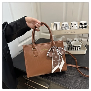 Détail du sac cabas marron à motif serpent avec foulard décoratif et lettrage doré