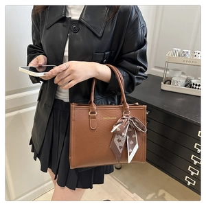 Détail du sac cabas marron gaufré avec foulard à motifs cœurs et logo de mode élégant