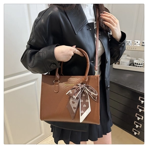 Détail du sac cabas en cuir gaufré avec lettrage doré et foulard en soie à motif de cœur
