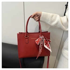 Détail du sac cabas rouge à motif serpent avec foulard en soie et lettrage doré