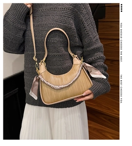 Detail of half-moon straw handbag with silk scarf handle and leather trim accents