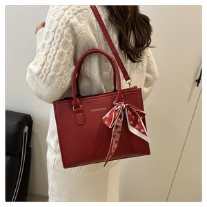 Détail d'un sac cabas rouge texturé serpent avec foulard en soie et bandoulière amovible
