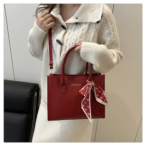 Détail du sac cabas rouge gaufré serpent avec foulard à cœurs et logo doré imprimé